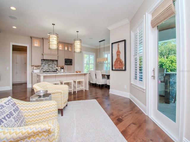 living room featuring dark wood-type flooring, ornamental molding, and a chandelier