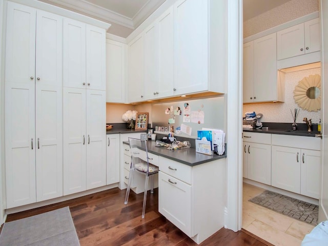 kitchen with white cabinetry, ornamental molding, and dark hardwood / wood-style flooring