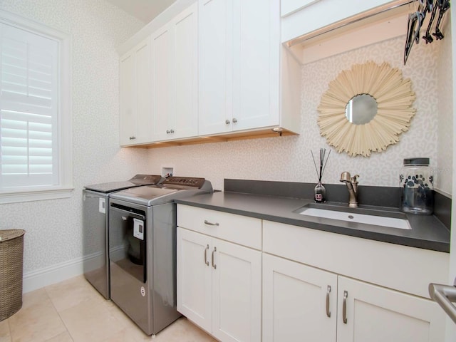 kitchen featuring white cabinets, washer and clothes dryer, sink, and light tile patterned floors