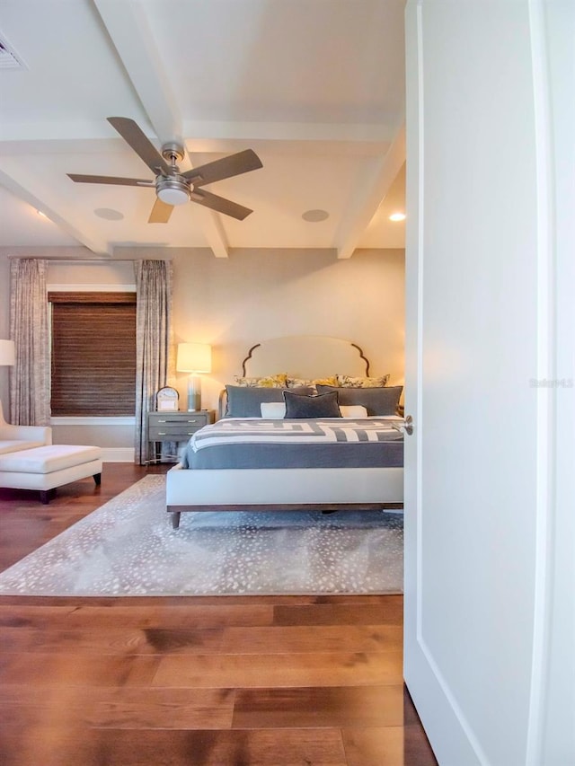 bedroom featuring ceiling fan, dark wood-type flooring, and beamed ceiling