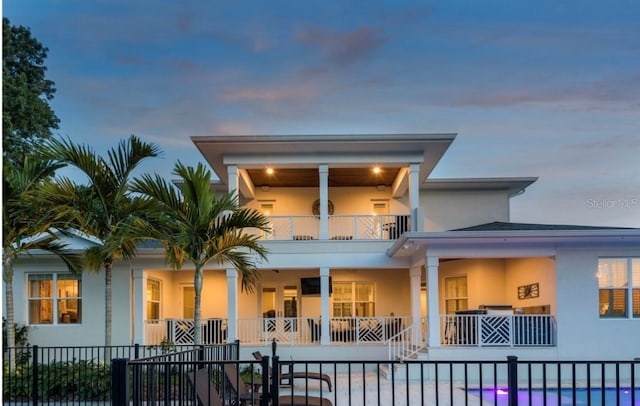 back house at dusk featuring a balcony