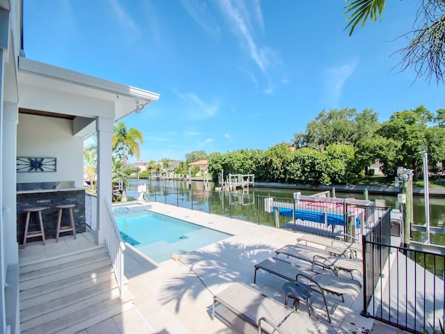 view of pool with a bar, a water view, and a patio