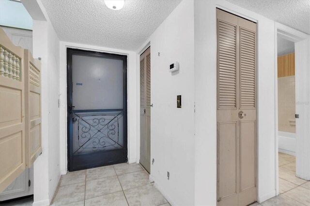 doorway to outside featuring light tile patterned floors and a textured ceiling