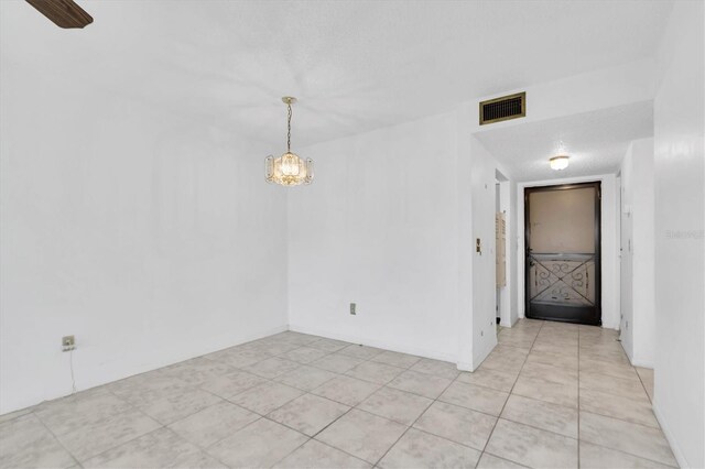 tiled spare room featuring a textured ceiling and ceiling fan with notable chandelier