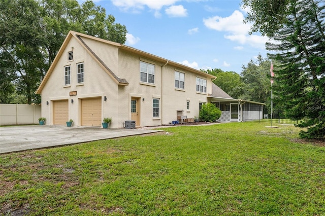 back of property featuring central AC, a garage, a lawn, and a sunroom