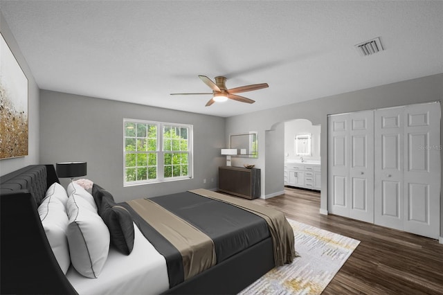 bedroom with ceiling fan, dark hardwood / wood-style flooring, a textured ceiling, and ensuite bath