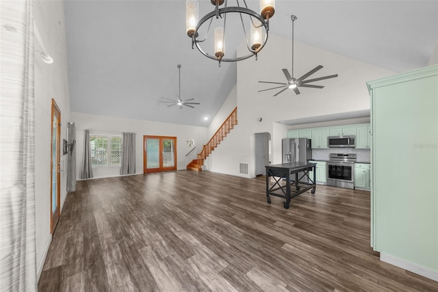 living room with ceiling fan with notable chandelier, dark hardwood / wood-style flooring, and high vaulted ceiling