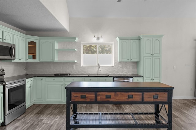 kitchen with a textured ceiling, sink, appliances with stainless steel finishes, and hardwood / wood-style floors