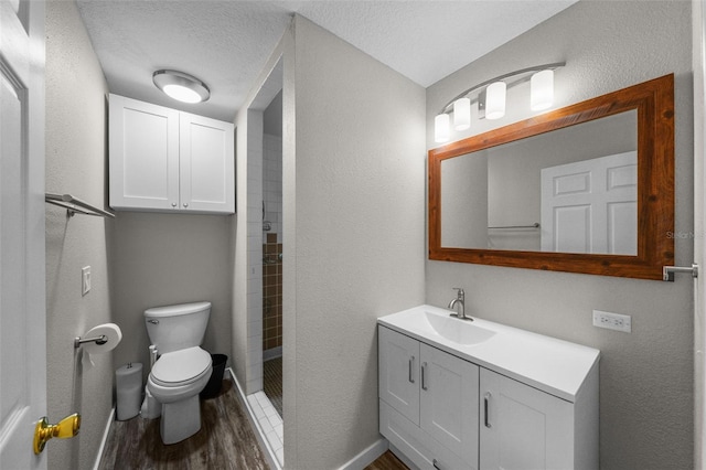 bathroom featuring walk in shower, vanity, a textured ceiling, wood-type flooring, and toilet