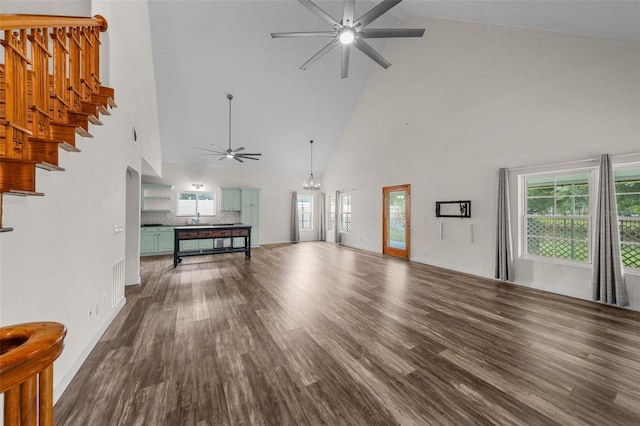 unfurnished living room with hardwood / wood-style floors, ceiling fan with notable chandelier, high vaulted ceiling, and sink