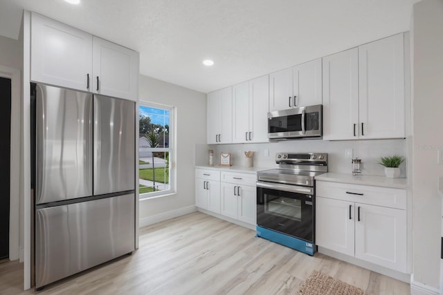 kitchen featuring stainless steel appliances, white cabinets, and light hardwood / wood-style floors