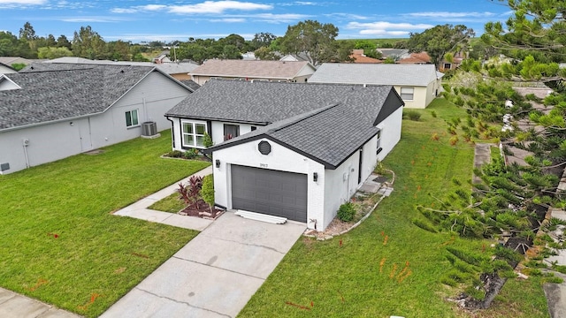 view of front of home featuring a garage, a front yard, and central air condition unit