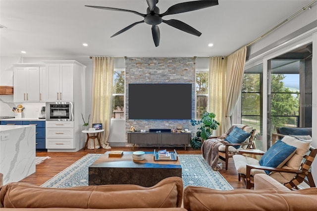 living room with ceiling fan, a fireplace, and light wood-type flooring