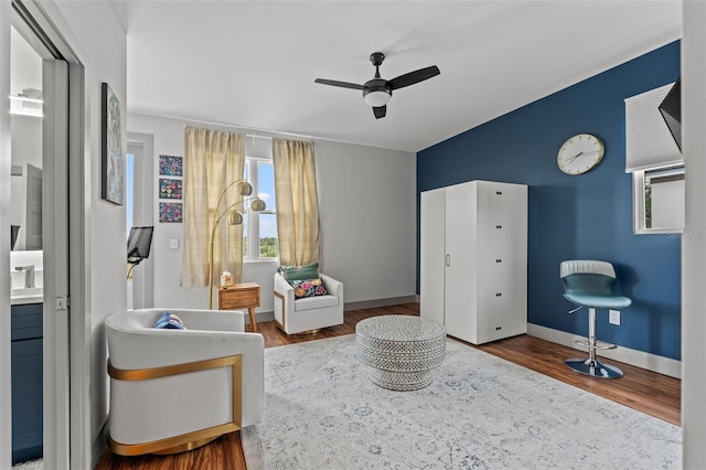 living area featuring ceiling fan, wood-type flooring, and sink