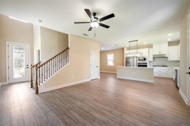 kitchen with white cabinets, appliances with stainless steel finishes, light hardwood / wood-style floors, ceiling fan, and a kitchen island