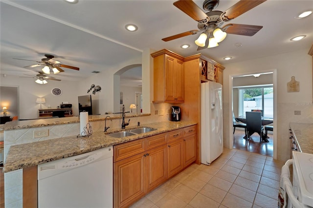 kitchen featuring white appliances, kitchen peninsula, light stone countertops, ceiling fan, and sink