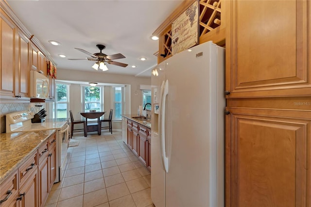 kitchen featuring decorative backsplash, light stone counters, white appliances, ceiling fan, and sink