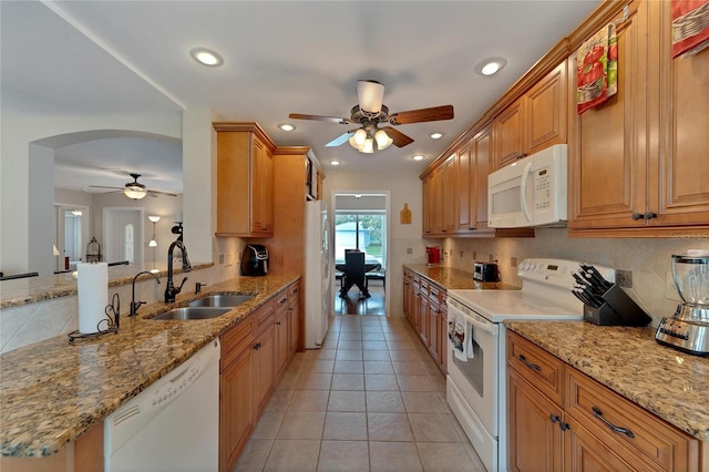 kitchen with light stone countertops, white appliances, sink, and ceiling fan