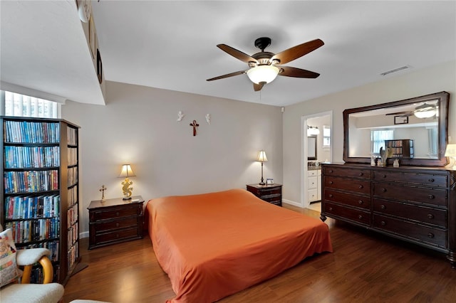 bedroom with ceiling fan, ensuite bath, and dark wood-type flooring