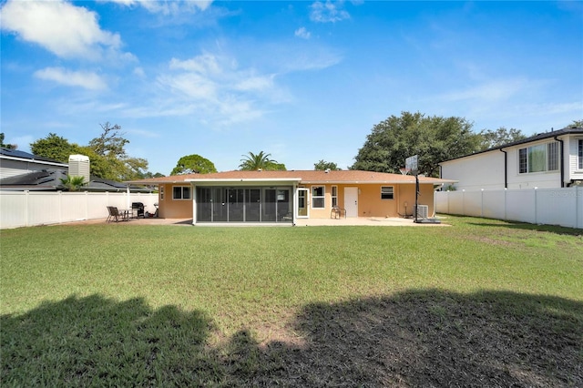 rear view of property featuring a sunroom, a lawn, and a patio area