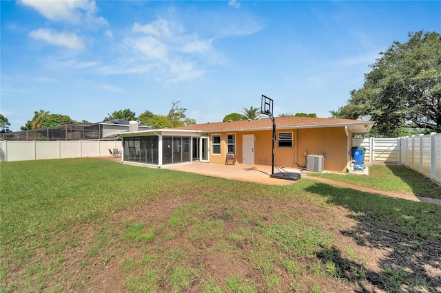 rear view of house featuring a sunroom, a patio, central air condition unit, and a yard