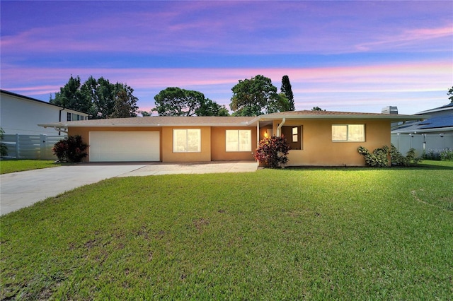 ranch-style home with a garage and a lawn