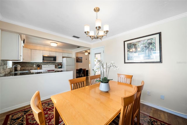 dining space featuring ornamental molding, sink, ceiling fan with notable chandelier, and hardwood / wood-style floors