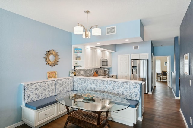 dining space with breakfast area, dark hardwood / wood-style flooring, and a chandelier