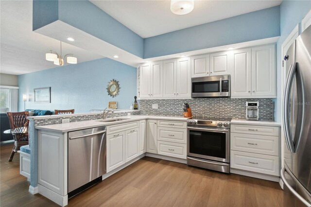 kitchen with white cabinetry, sink, stainless steel appliances, light hardwood / wood-style flooring, and kitchen peninsula