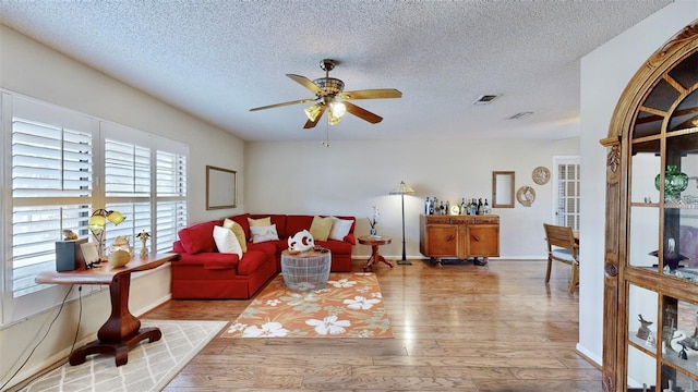 living room with a textured ceiling, light hardwood / wood-style flooring, and ceiling fan