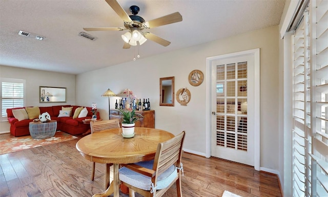 dining space with a textured ceiling, wood-type flooring, and ceiling fan