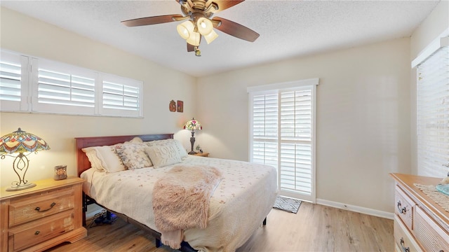 bedroom with a textured ceiling, light hardwood / wood-style flooring, and ceiling fan