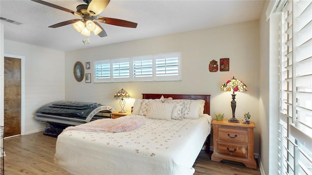 bedroom with ceiling fan, hardwood / wood-style flooring, and a textured ceiling