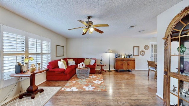 living room with ceiling fan, light hardwood / wood-style floors, and a textured ceiling