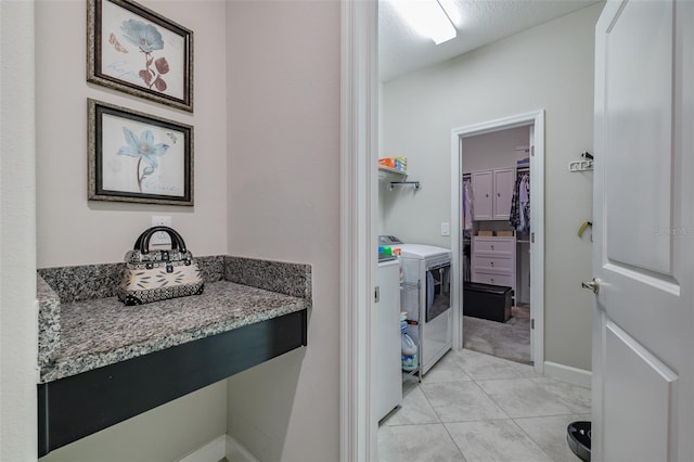 laundry area with a textured ceiling, washing machine and dryer, and light tile patterned flooring