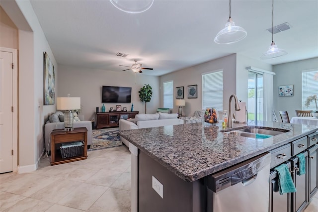 kitchen with a center island with sink, hanging light fixtures, stainless steel dishwasher, sink, and ceiling fan