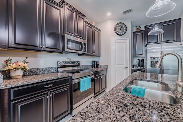 kitchen with appliances with stainless steel finishes, hanging light fixtures, sink, and dark brown cabinets