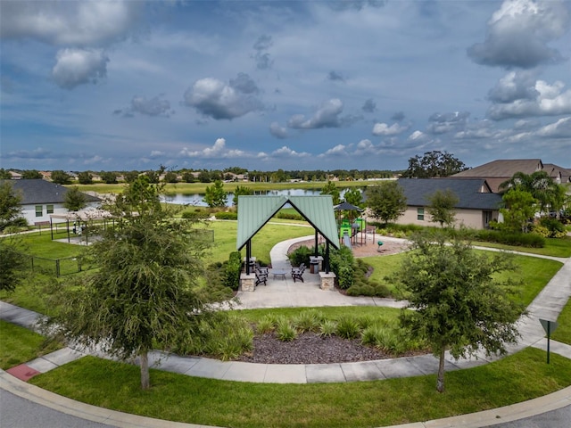 view of property's community featuring a playground, a lawn, and a water view