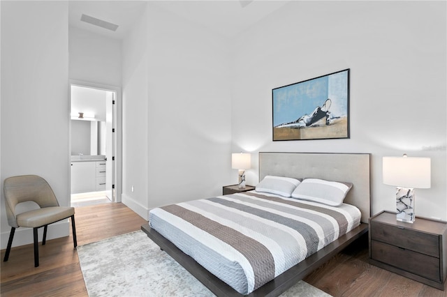 bedroom with hardwood / wood-style floors and ensuite bath