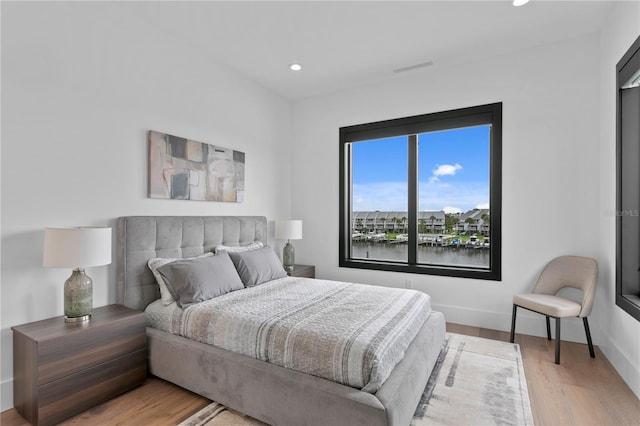 bedroom featuring light hardwood / wood-style floors and a water view