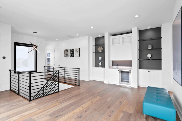 living room featuring built in shelves, light hardwood / wood-style flooring, and a notable chandelier