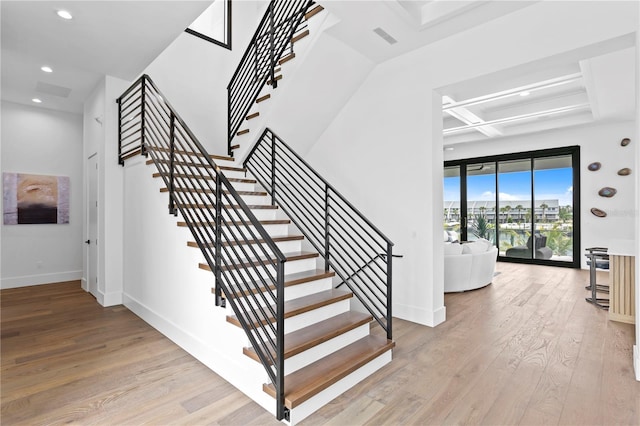 staircase with beam ceiling, wood-type flooring, and coffered ceiling