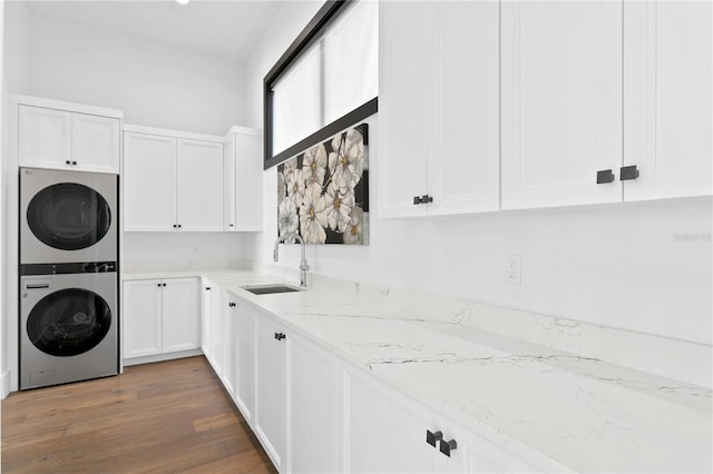 washroom with stacked washer / drying machine, dark hardwood / wood-style flooring, cabinets, and sink