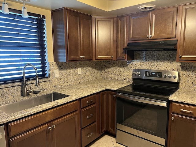 kitchen featuring electric stove, light stone counters, light tile patterned floors, dark brown cabinets, and sink