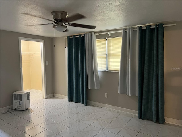 unfurnished bedroom featuring ceiling fan, a textured ceiling, a closet, and a spacious closet