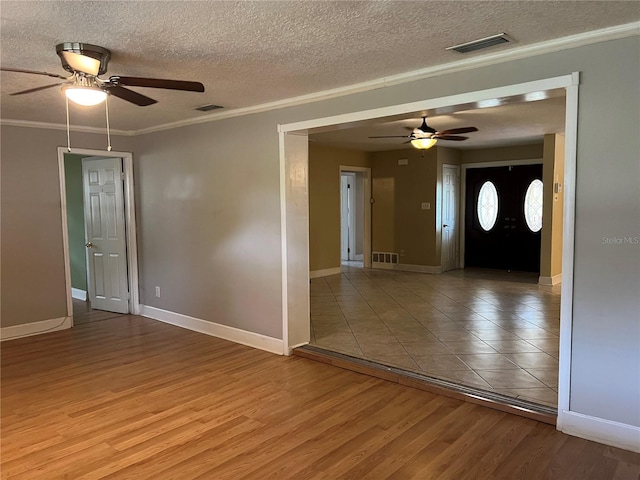 empty room with light wood-type flooring, a textured ceiling, ornamental molding, and ceiling fan