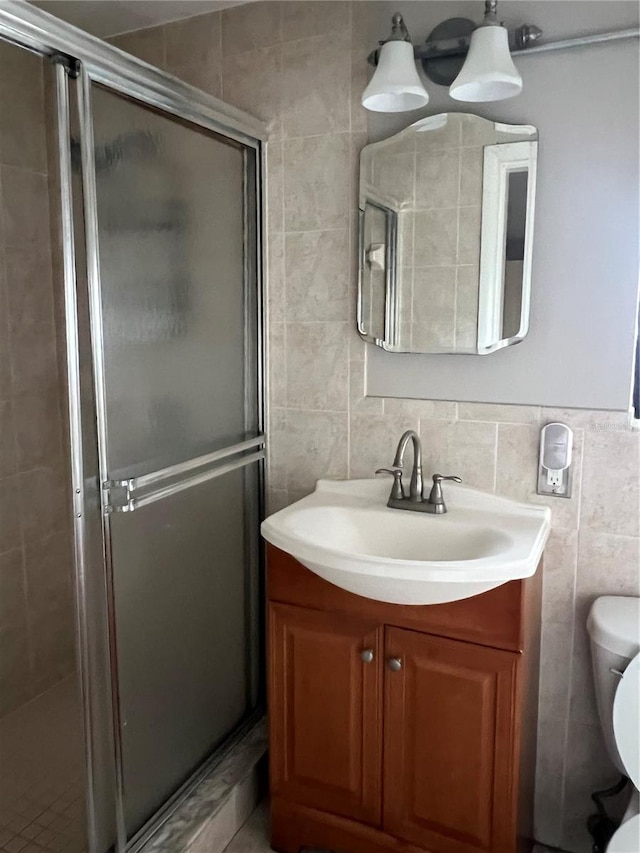 bathroom with vanity, tile walls, toilet, and an enclosed shower