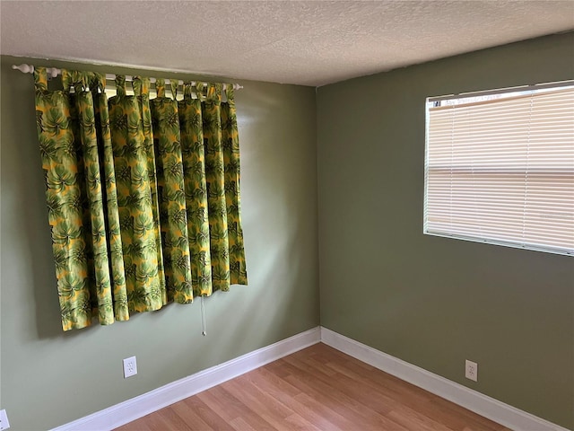 empty room with wood-type flooring and a textured ceiling