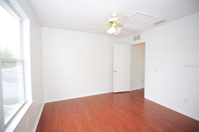 empty room with a textured ceiling, ceiling fan, and dark hardwood / wood-style flooring