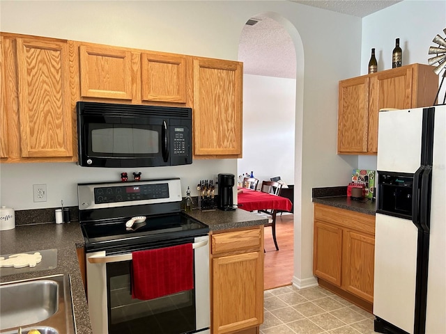 kitchen featuring white fridge with ice dispenser, a textured ceiling, and stainless steel electric range